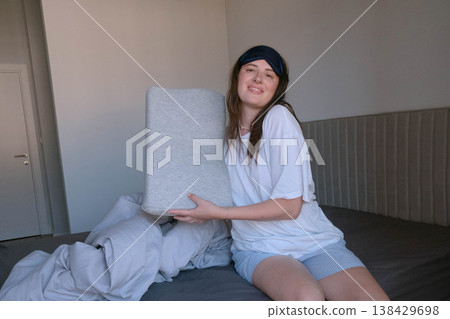 Girl in cozy bedroom holding orthopedic pillow providing spine support and relieving neck and back discomfort for healthy sleep Girl in cozy bedroom holding orthopedic pillow providing spine support and relieving neck and back discomfort for healthy sleep 138429698