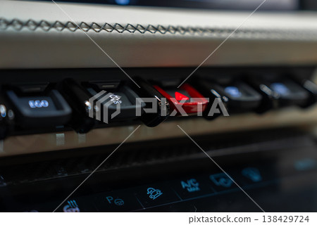 Close up shows stitched leather trim, toggle style switches, and a red hazard button. Glossy touch panel shows icons for parking sensors, A C, and seat controls indoors. Close up shows stitched leather trim, toggle style switches, and a red hazard button. Glossy touch panel shows icons for parking sensors, A C, and seat controls indoors. 138429724