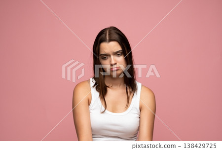 Young woman feeling sad and dejected, experiencing melancholy or depression, posing on a pink background 138429725