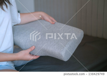 Woman holding orthopedic pillow before sleep showing care for health proper posture and importance of comfort and ergonomic design for quality rest 138429749