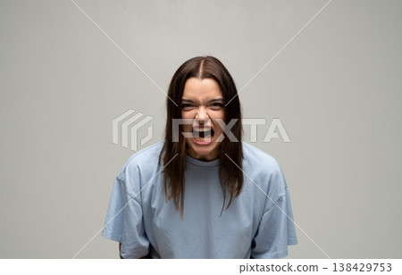 Young woman aggressively screaming, expressing furious anger, stress, and frustration with a wide open mouth Young woman aggressively screaming, expressing furious anger, stress, and frustration with a wide open mouth 138429753