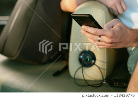 Hand plugging phone into charger in airport seat showing modern travel convenience with easy access to power and connection anywhere on the journey 138429776