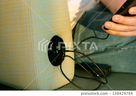 Hand connecting phone to charger in airport seat symbol of modern travel convenience with easy access to power and connection anywhere on the journey Hand connecting phone to charger in airport seat symbol of modern travel convenience with easy access to power and connection anywhere on the journey 138429784
