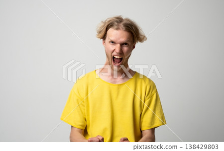 Young man yelling, expressing extreme anger and frustration with an aggressive face and open mouth, symbolizing strong negative emotions, stress, rage, and a feeling of being upset 138429803