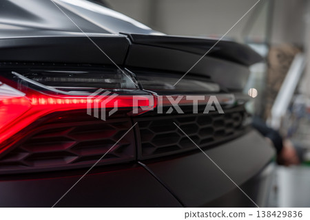 Tight view shows Lamborghini Urus style rear left corner in an indoor service bay, LED taillight illuminated, honeycomb grille texture, matte paint, soft industrial lighting Tight view shows Lamborghini Urus style rear left corner in an indoor service bay, LED taillight illuminated, honeycomb grille texture, matte paint, soft industrial lighting 138429836
