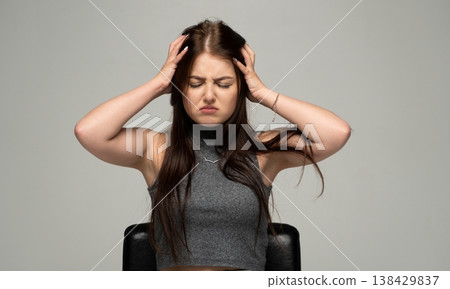 Young woman suffering from headache or migraine, feeling frustrated and stressed, holding hands to head Young woman suffering from headache or migraine, feeling frustrated and stressed, holding hands to head 138429837
