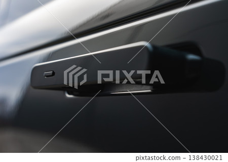 A close up shows a flush pop out door handle with sensor button on a glossy black SUV in an indoor detailing bay, soft light and shallow depth of field emphasize design. A close up shows a flush pop out door handle with sensor button on a glossy black SUV in an indoor detailing bay, soft light and shallow depth of field emphasize design. 138430021