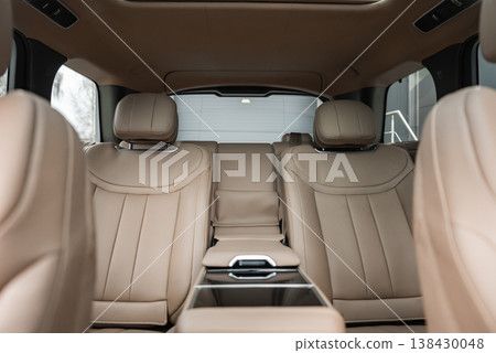 Wide angle view shows tan leather seats, quilted backs, and glossy black console in a luxury Range Rover Autobiography. Interior sits in a well lit workshop, with clean, even lighting. 138430048
