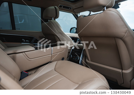 Close up interior view shows tan leather rear seats, center armrest, premium door trim, and rear climate controls in a modern showroom, with soft, even lighting. Close up interior view shows tan leather rear seats, center armrest, premium door trim, and rear climate controls in a modern showroom, with soft, even lighting. 138430049