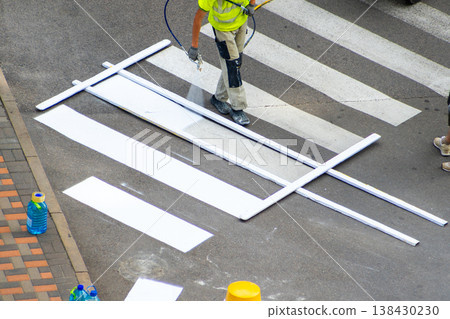Road Worker Painting Pedestrian Crossing. Applying markings. Paint spray white color line. Highway crosswalk mark working man Road Worker Painting Pedestrian Crossing. Applying markings. Paint spray white color line. Highway crosswalk mark working man 138430230