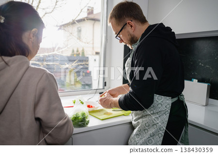 Couple preparing fresh vegetables together in home kitchen 138430359
