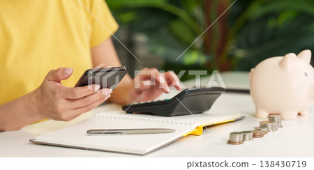 Woman managing finances with phone and calculator 138430719