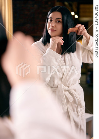 Woman combing straight hair in mirror at home. Woman combing straight hair in mirror at home. 138430805
