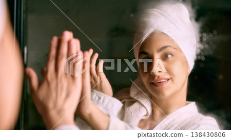 Woman touching mirror with hands during beauty routine. Woman touching mirror with hands during beauty routine. 138430806