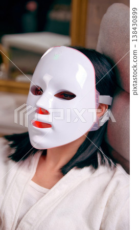 Close up of woman using led light therapy facial mask. 138430899