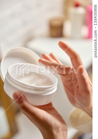 Hand holding cosmetic cream jar with soft texture close up. Hand holding cosmetic cream jar with soft texture close up. 138430906