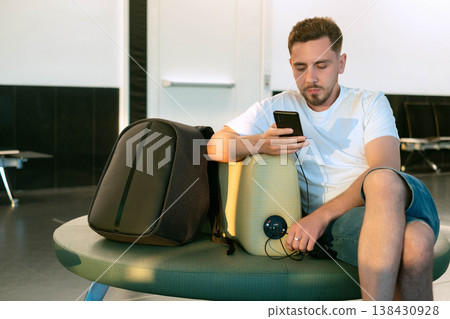 Man working in airport waiting lounge using built in charging stations modern infrastructure enables comfort and staying connected anywhere in the world Man working in airport waiting lounge using built in charging stations modern infrastructure enables comfort and staying connected anywhere in the world 138430928