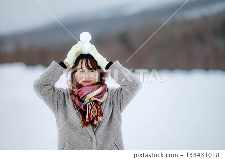一位年輕女子抱著一個雪人 一位年輕女子抱著一個雪人 138431018