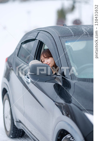 一位年輕女子在冬日的雪地裡開車。 138431632