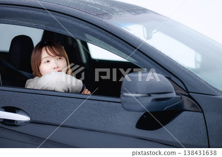 A young woman driving a car in the winter snow. A young woman driving a car in the winter snow. 138431638