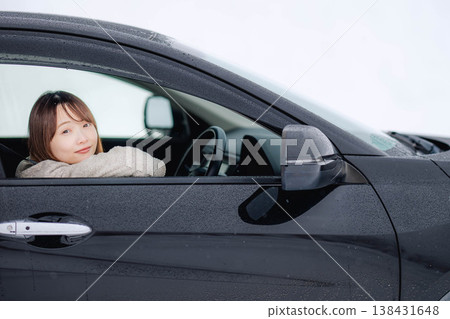 一位年輕女子在冬日的雪地裡開車。 一位年輕女子在冬日的雪地裡開車。 138431648
