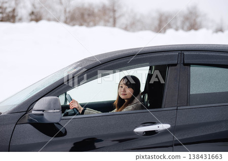 一位年輕女子在冬日的雪地裡開車。 一位年輕女子在冬日的雪地裡開車。 138431663