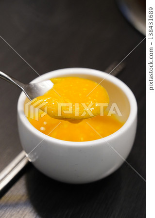 Close-up of creamy Korean pumpkin porridge (Hobak-juk) in a white bowl with a spoon 138431689