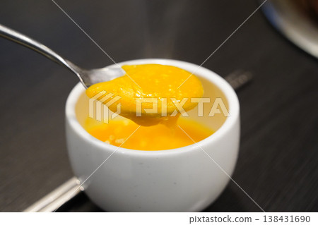 Close-up of creamy Korean pumpkin porridge (Hobak-juk) in a white bowl with a spoon Close-up of creamy Korean pumpkin porridge (Hobak-juk) in a white bowl with a spoon 138431690