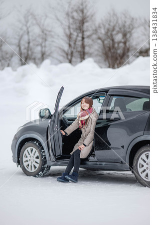 冬日雪地裡,一位年輕女子坐在車裡。 冬日雪地裡,一位年輕女子坐在車裡。 138431834
