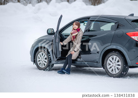 冬日雪地裡,一位年輕女子坐在車裡。 冬日雪地裡,一位年輕女子坐在車裡。 138431838