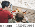 Close-up view of father and his school boy son on a family picnic in the mountains. Child kid and his dad taking a rest and enjoying a picnic while hiking in the mountains 138431994
