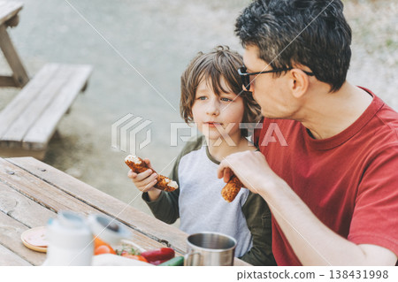 Close-up view of father hugs his school boy son on a family picnic in the mountains. Child kid and his dad taking a rest and enjoying a picnic while hiking in the mountains 138431998