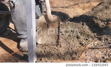 Worker Shoveling Mortar Into House Construction Area, Dynamic Action Of Shovel Scooping Wet Mix From Pile, Boots And Gloves In Motion, Dirt And Foundation Edge Visible, Physical Effort Worker Shoveling Mortar Into House Construction Area, Dynamic Action Of Shovel Scooping Wet Mix From Pile, Boots And Gloves In Motion, Dirt And Foundation Edge Visible, Physical Effort 138432047