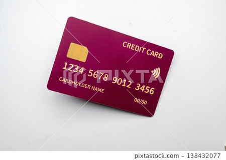 A close-up shot of a vibrant magenta plastic credit card featuring a gold chip, contactless payment icon, card numbers, and placeholders for name and date, set against a plain white surface A close-up shot of a vibrant magenta plastic credit card featuring a gold chip, contactless payment icon, card numbers, and placeholders for name and date, set against a plain white surface 138432077