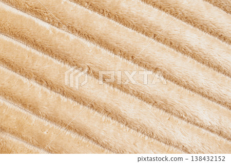 Macro photo of a cozy beige blanket with a soft ribbed texture. The diagonal knit pattern and warm cream tones create a tactile, hygge inspired background for home decor 138432152