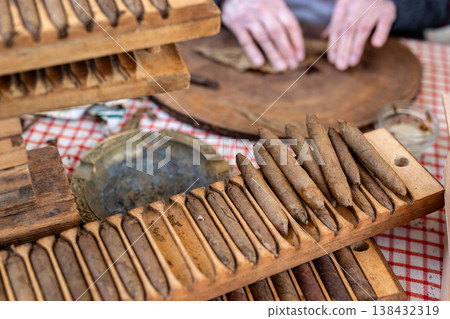 Wooden cigar molds filled rolled tobacco cigars display table during traditional handmade production process. Artisan workshop scene classic tool shape pressing cigars historic tobacco craft industry 138432319