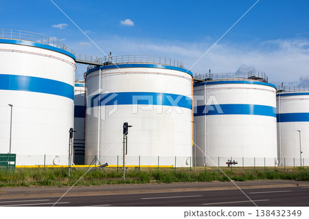 Row many large industrial fuel storage white tanks clear blue sky background on sunny day. Oil storage refinery depot liquid facilities. Energy hazmat railroad transportation storage and distribution 138432349