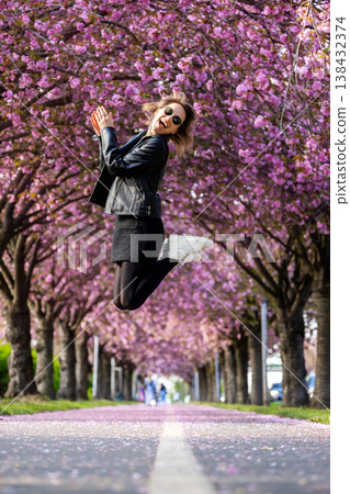 Dynamic scenic young adult pretty happy woman enjoy walking spring city street blooming pink cherry trees alley background in Magdeburg city. Female person joyful carefree portrait smiling outdoors Dynamic scenic young adult pretty happy woman enjoy walking spring city street blooming pink cherry trees alley background in Magdeburg city. Female person joyful carefree portrait smiling outdoors 138432374