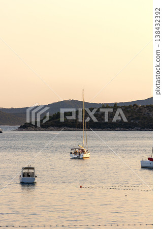 Sailboats anchored calm sea bay mediterranean coast green hills clear sky during warm summer evening. Scenic marine landscape yachts travel leisure atmosphere tranquil seaside tourism destination 138432392