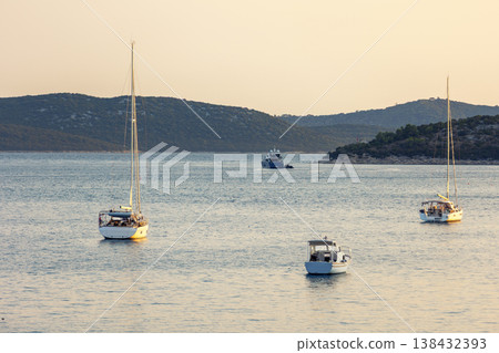 Sailboats anchored calm sea bay mediterranean coast green hills clear sky during warm summer evening. Scenic marine landscape yachts travel leisure atmosphere tranquil seaside tourism destination 138432393