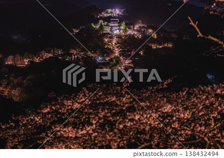 典型的日本風景：吉野山上夜晚的櫻花和燈火通明的寺廟。 138432494
