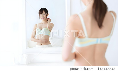 清晨，一位女士對著鏡子微笑，穿上她最喜歡的內衣。 138432838