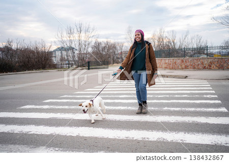 Young adult woman walking dog on crosswalk in city Young adult woman walking dog on crosswalk in city 138432867