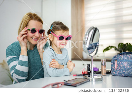 Mother and daughter bonding trying on funny sunglasses indoors Mother and daughter bonding trying on funny sunglasses indoors 138432886