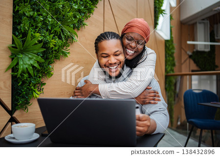 Happy couple embracing, doing online shopping using laptop Happy couple embracing, doing online shopping using laptop 138432896