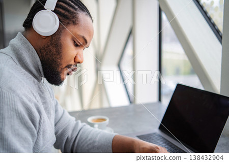 Young adult man listening headphones working laptop 138432904
