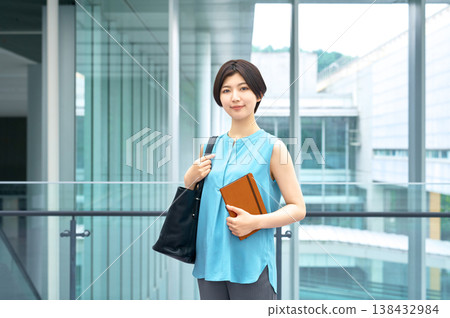 一位女商人面帶微笑,手裡拿著筆記本,站在辦公大樓燈火通明的走廊。 一位女商人面帶微笑,手裡拿著筆記本,站在辦公大樓燈火通明的走廊。 138432984