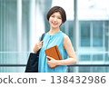 一位笑容燦爛的女商人手持筆記本,站在辦公大樓裡。 一位笑容燦爛的女商人手持筆記本,站在辦公大樓裡。 138432986