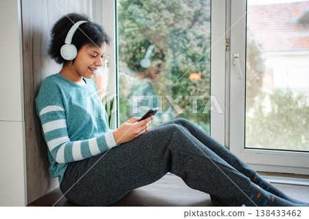 Young woman listening to music on headphones using smartphone Young woman listening to music on headphones using smartphone 138433462