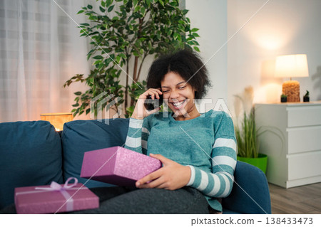 Young woman laughing, talking on smartphone receiving gifts Young woman laughing, talking on smartphone receiving gifts 138433473